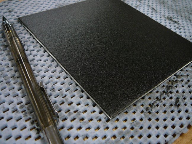 black ink on a metal plate sitting on non-skid support with a technical pencil nearby