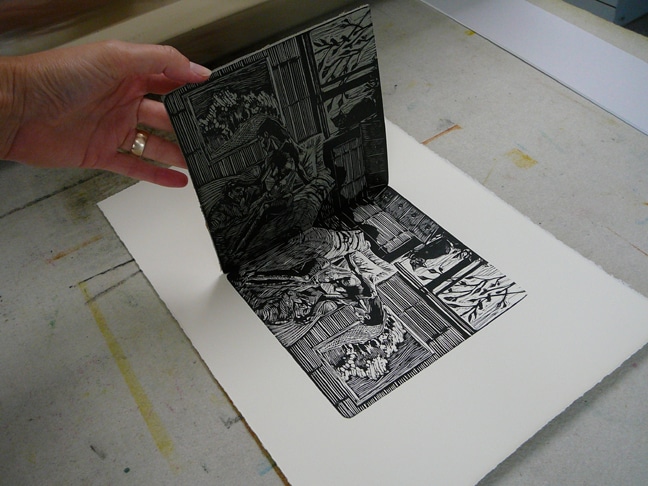 pulling a linoleum block after transferring ink to paper on a press