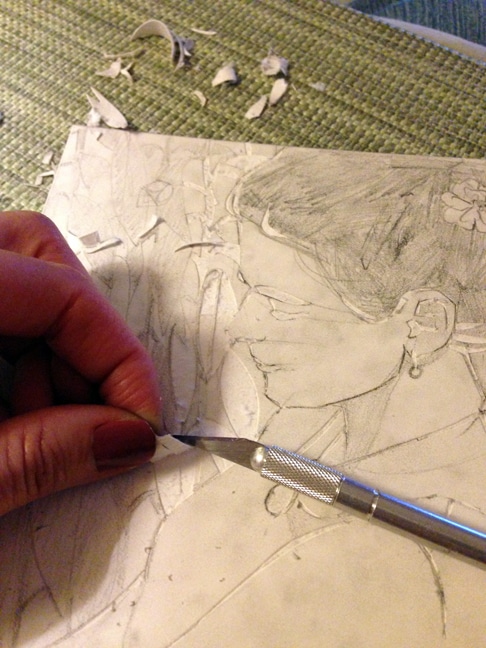 Using a blade to carve a shallow upper-layer from the mat board which will leave recessed shapes to hold ink