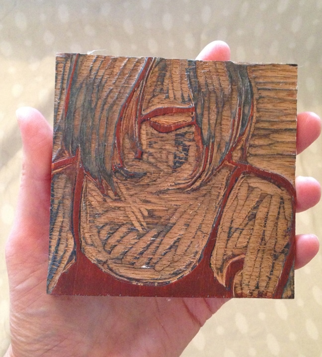A wood block with a carving of a woman's face
