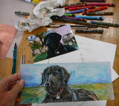 Making the monotype on a table with a reference photo of a black great dane and a pile of caran d'ache crayons strewn about