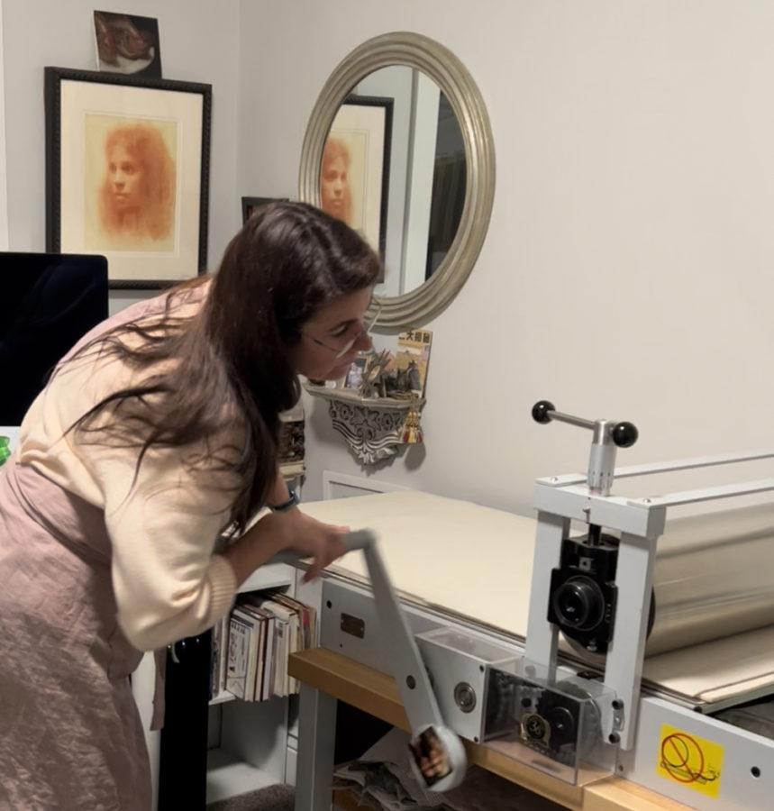 Belinda Del Pesco running a print through her Takach etching press in her art studio