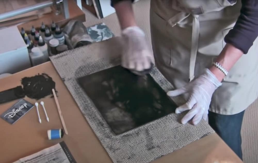 a printmaker in her studio wiping ink from a drypoint plate