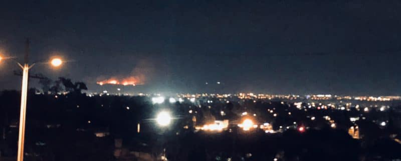 a night time horizon photo of ventura looking south at a mountain range on fire in the distance
