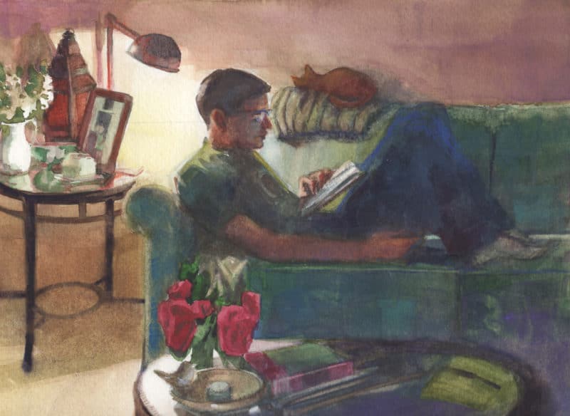 a boy reading a book on a couch near a single lamp in a cozy room with a cat