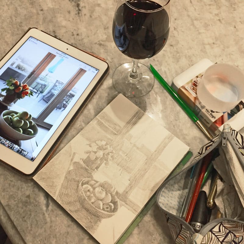 an ipad with a reference photo, a glass of red wine and a sketch in process